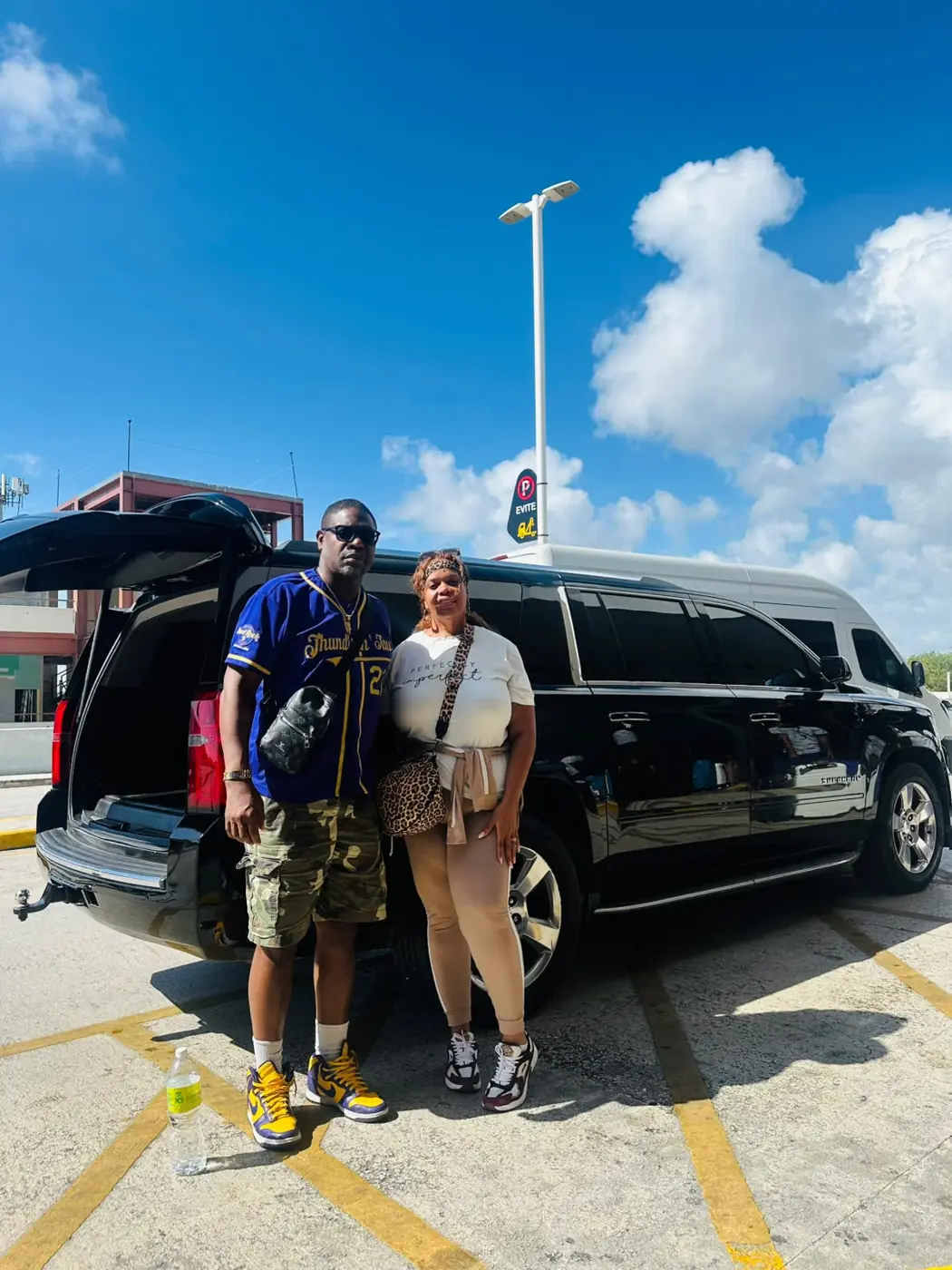 A couple with their luggage next to their black Suburban at Punta Cana Airport